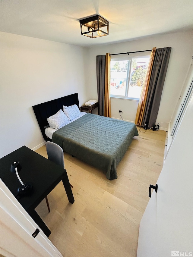 bedroom featuring an inviting chandelier and light hardwood / wood-style floors