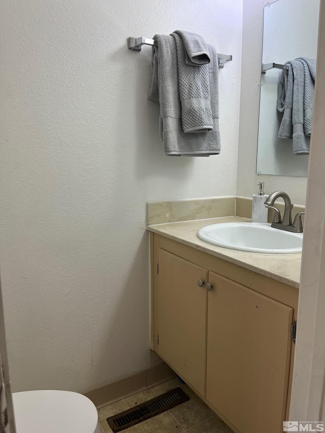 bathroom with tile patterned flooring, vanity, and toilet