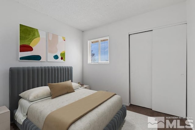 carpeted bedroom with a closet and a textured ceiling