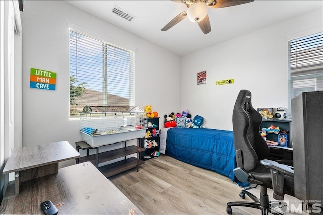 bedroom featuring ceiling fan, light wood-type flooring, and multiple windows