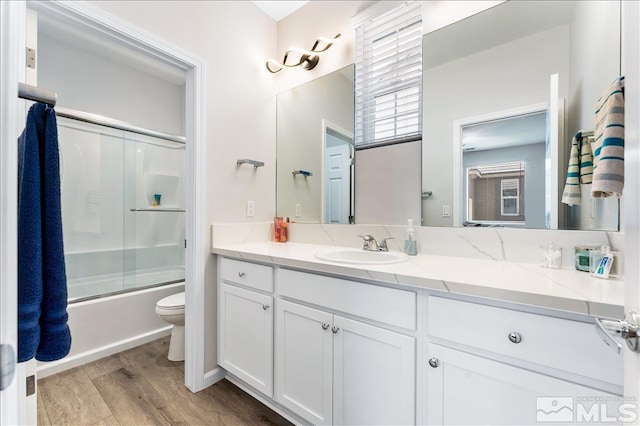 full bathroom featuring toilet, vanity, wood-type flooring, and shower / bath combination with glass door