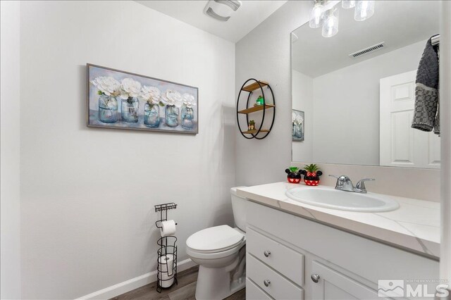 bathroom featuring toilet, vanity, and wood-type flooring