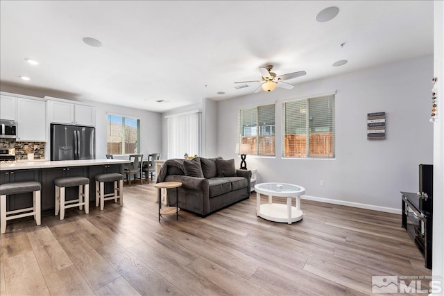 living room featuring ceiling fan and light hardwood / wood-style floors