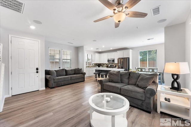 living room featuring ceiling fan and light hardwood / wood-style flooring