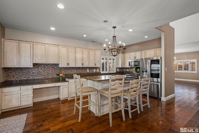 kitchen featuring a breakfast bar, sink, hanging light fixtures, appliances with stainless steel finishes, and dark hardwood / wood-style flooring