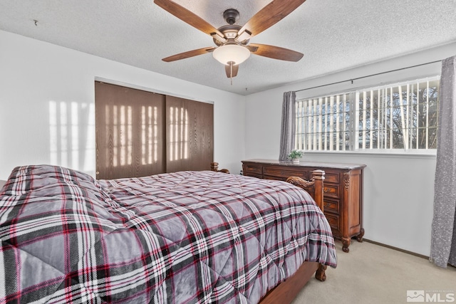 carpeted bedroom featuring a textured ceiling and ceiling fan