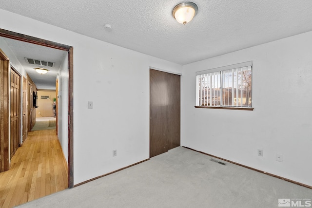 unfurnished bedroom with a textured ceiling, a closet, and light carpet