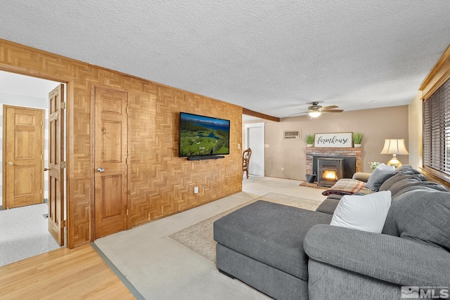 living room featuring ceiling fan, a textured ceiling, and light wood-type flooring