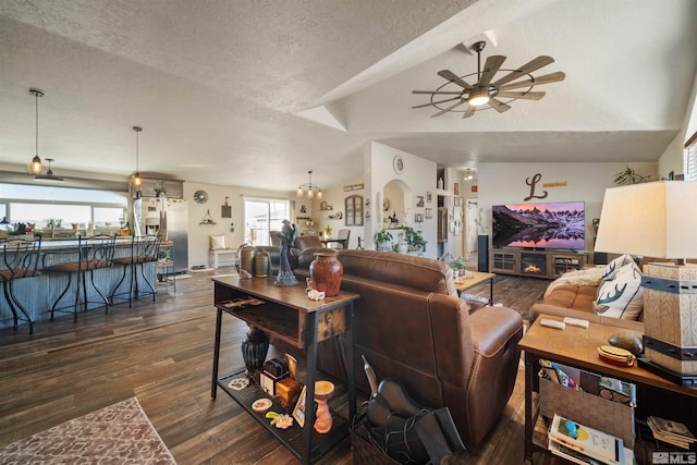 living room featuring ceiling fan, vaulted ceiling, dark hardwood / wood-style flooring, and a textured ceiling