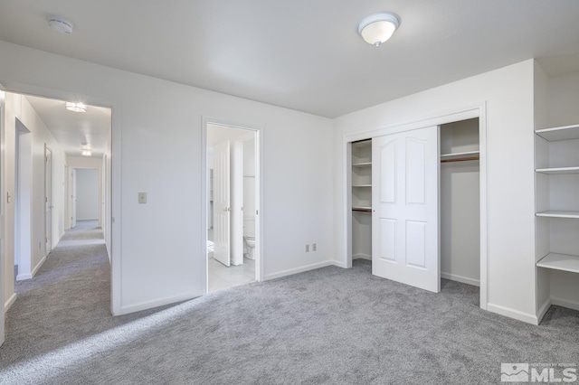 unfurnished bedroom with light carpet, a closet, and ensuite bath