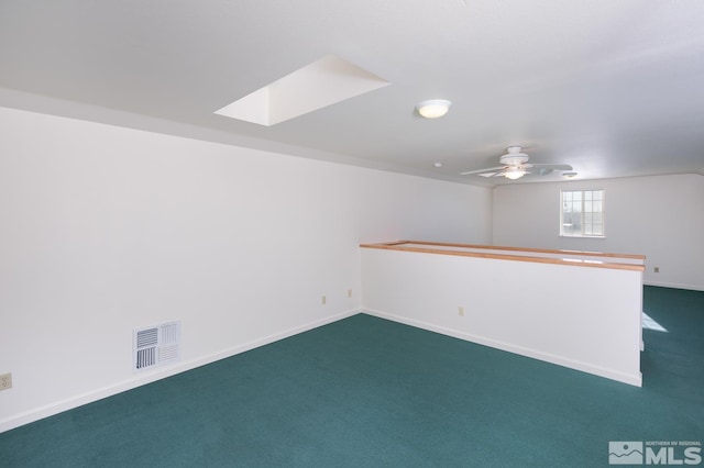 basement with ceiling fan and dark colored carpet