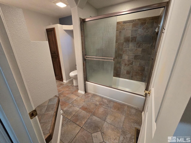 bathroom with bath / shower combo with glass door and toilet