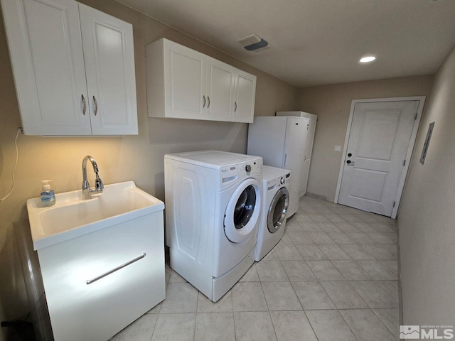 clothes washing area with cabinets, light tile patterned flooring, and separate washer and dryer