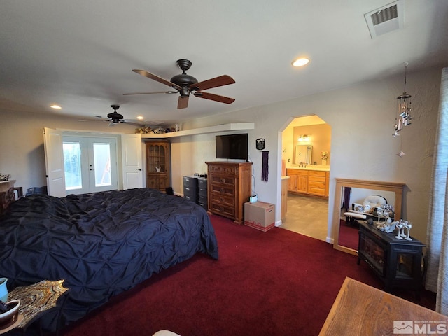 carpeted bedroom with ensuite bathroom, ceiling fan, and french doors