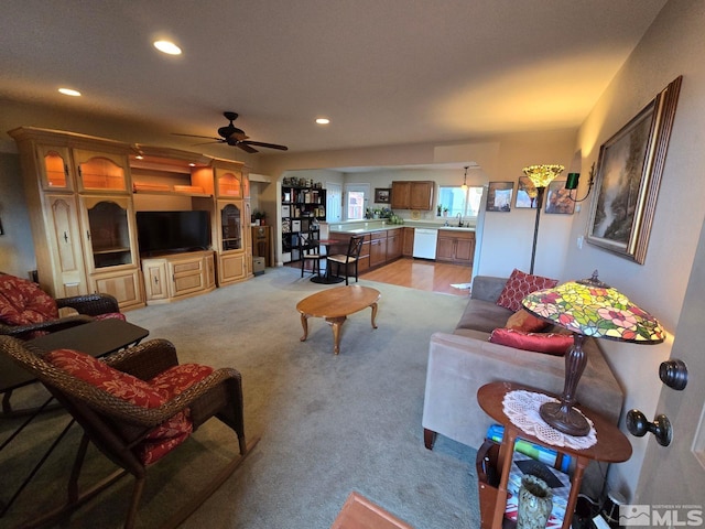 living room featuring ceiling fan, sink, and light carpet