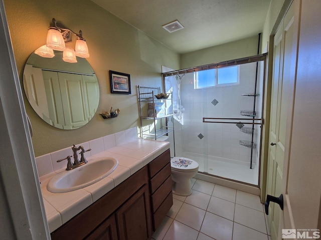 bathroom featuring tile patterned flooring, vanity, toilet, and walk in shower