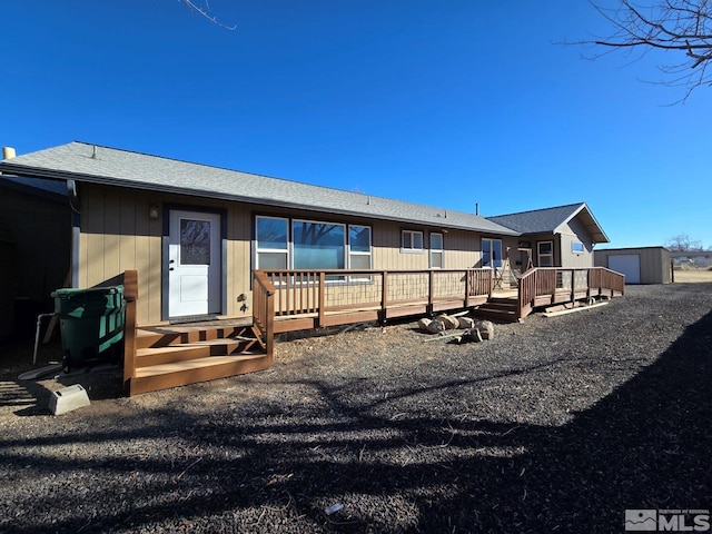 rear view of property with a wooden deck and a storage shed