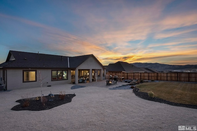 back house at dusk featuring central air condition unit, a mountain view, and a patio