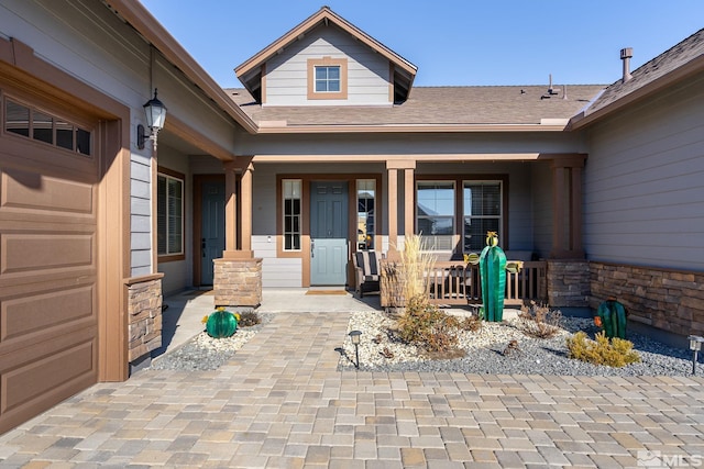 view of exterior entry featuring a garage and a porch