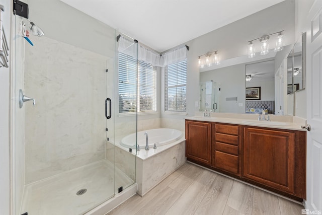 bathroom with ceiling fan, shower with separate bathtub, hardwood / wood-style floors, and vanity