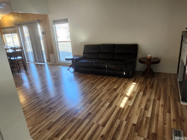 living room with dark wood-type flooring, vaulted ceiling, and a healthy amount of sunlight