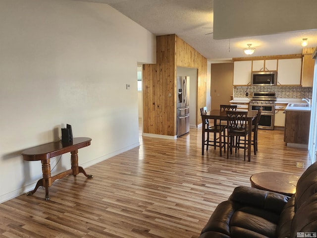 living room featuring light hardwood / wood-style floors, sink, high vaulted ceiling, and ceiling fan