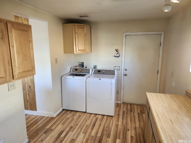 clothes washing area with light wood-type flooring, cabinets, and washer and dryer