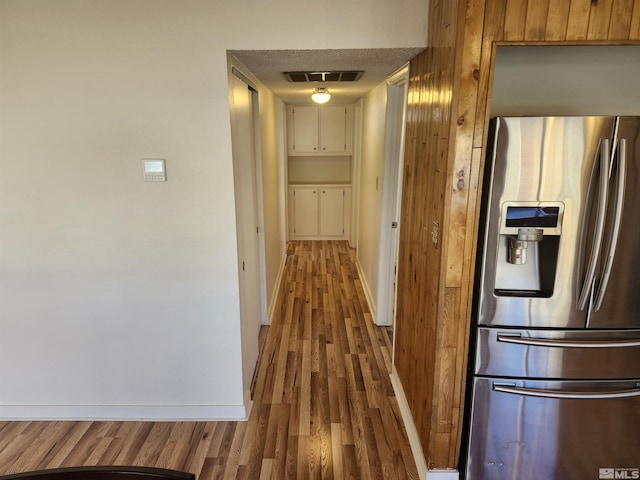 corridor with wood-type flooring and a textured ceiling