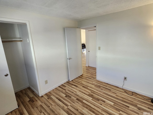 unfurnished bedroom featuring a textured ceiling, a closet, and hardwood / wood-style flooring