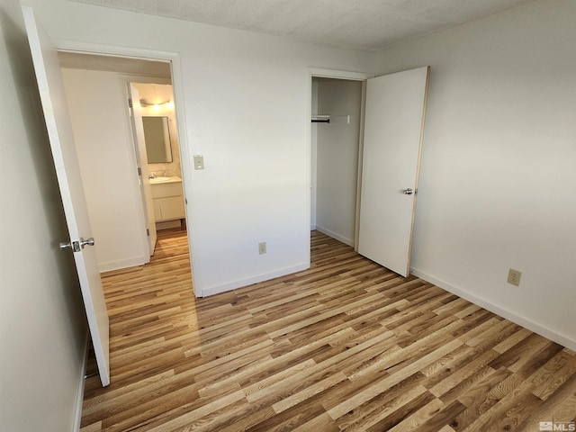 unfurnished bedroom with light hardwood / wood-style floors, sink, and a textured ceiling