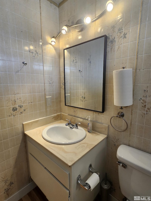 bathroom with tile walls, toilet, and vanity