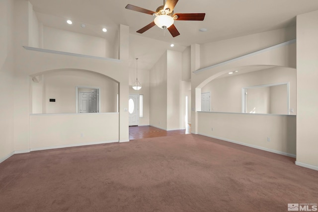 unfurnished living room featuring high vaulted ceiling, ceiling fan, and carpet flooring