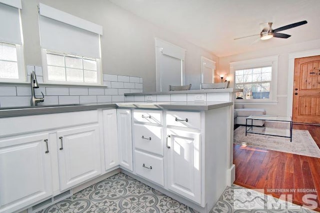 kitchen featuring tasteful backsplash, white cabinets, kitchen peninsula, and sink