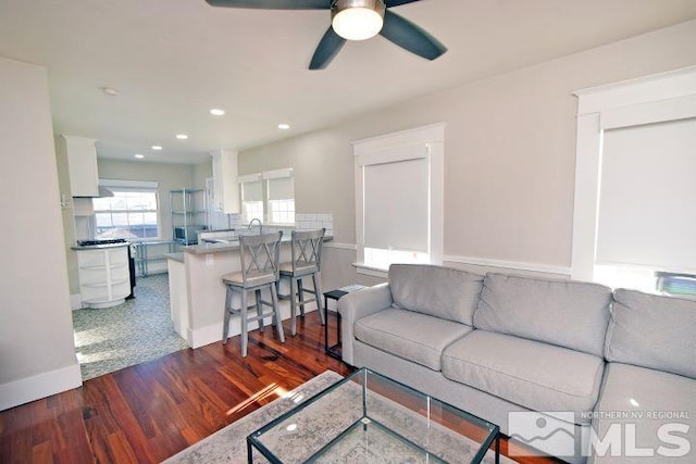 living room with ceiling fan and dark wood-type flooring