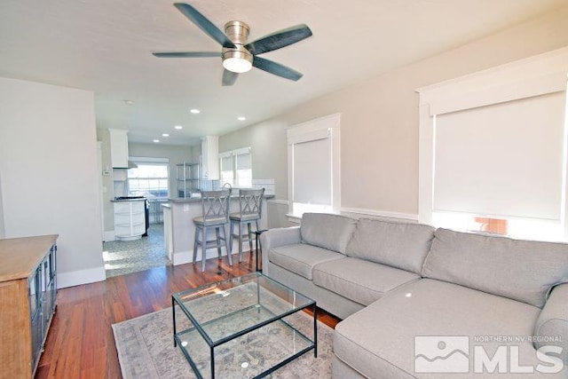 living room featuring ceiling fan and dark hardwood / wood-style floors