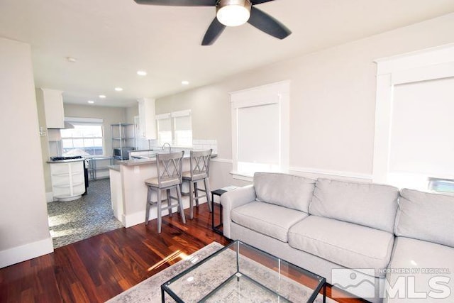 living room with ceiling fan and dark wood-type flooring