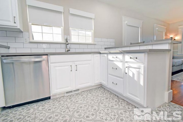 kitchen featuring tasteful backsplash, dishwasher, kitchen peninsula, light tile patterned floors, and white cabinets