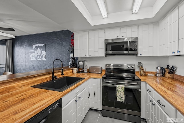 kitchen with sink, white cabinetry, butcher block counters, and stainless steel appliances