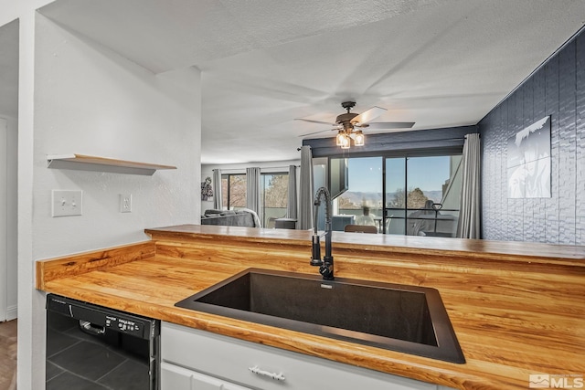 kitchen featuring ceiling fan, dishwasher, sink, and a textured ceiling