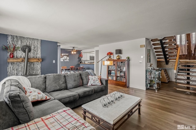 living room with hardwood / wood-style flooring, a wood stove, and ceiling fan