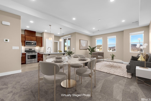 carpeted dining room with sink and a tray ceiling