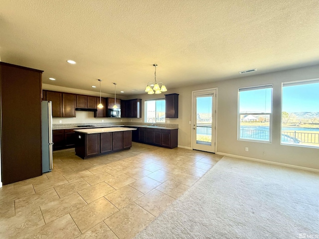 kitchen with pendant lighting, dark brown cabinetry, a center island, and appliances with stainless steel finishes