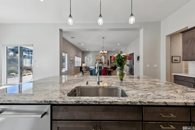 kitchen with pendant lighting, light stone countertops, and dark brown cabinetry