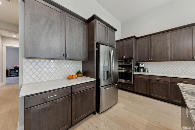 kitchen featuring decorative backsplash, dark brown cabinets, stainless steel appliances, and light hardwood / wood-style floors