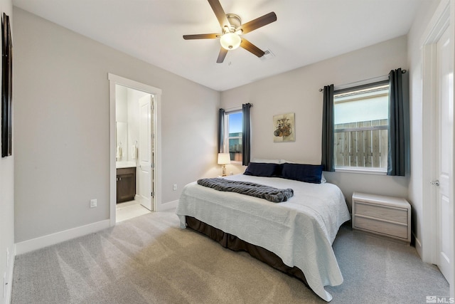 carpeted bedroom featuring multiple windows, ensuite bathroom, and ceiling fan