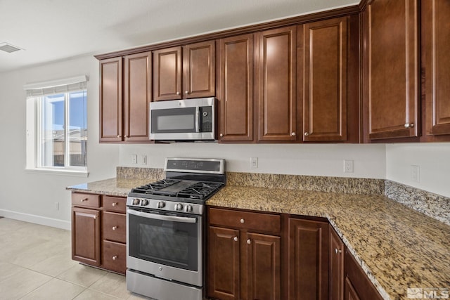 kitchen featuring light stone counters, light tile patterned floors, and stainless steel appliances