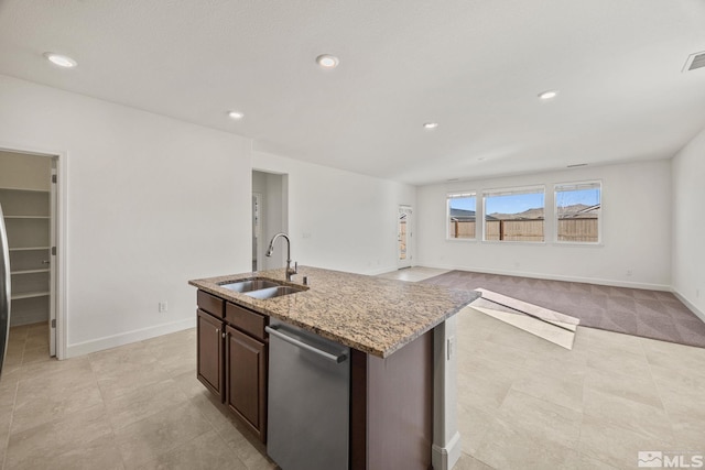 kitchen with dishwasher, sink, light stone counters, an island with sink, and dark brown cabinetry