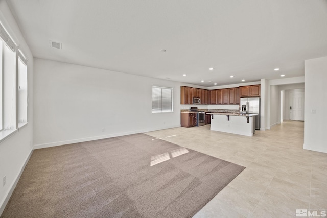 kitchen featuring an island with sink, a kitchen bar, and appliances with stainless steel finishes