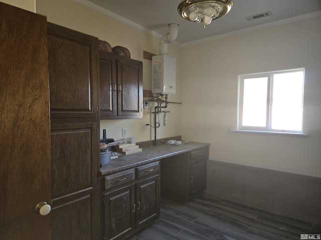 kitchen featuring tankless water heater, ornamental molding, dark hardwood / wood-style floors, dark stone countertops, and dark brown cabinetry