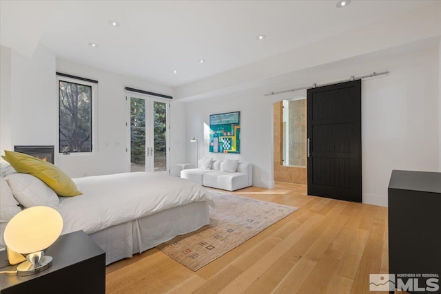 bedroom with french doors, a barn door, and light wood-type flooring